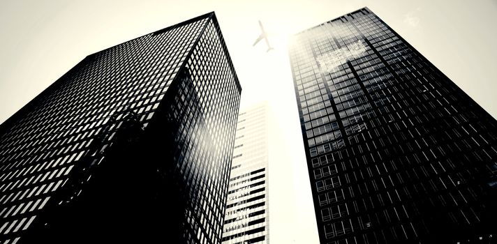 An airplane flying over buildings with the sun shining