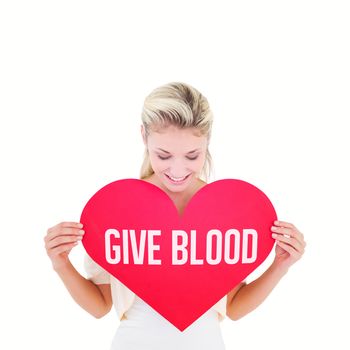 Attractive young blonde showing red heart against give blood