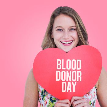 Woman holding heart card  against pink