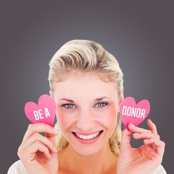 Attractive young blonde holding little hearts  against grey vignette