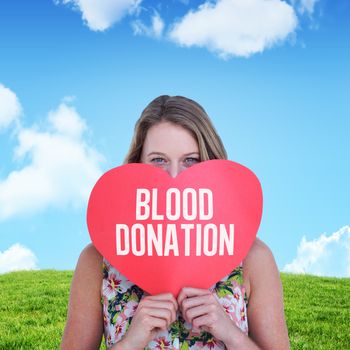 Woman holding heart card  against sky and field