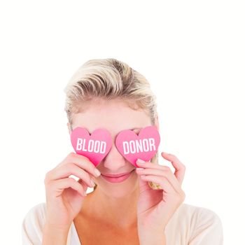 Attractive young blonde holding hearts over eyes against blood donor
