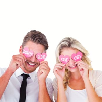 Attractive young couple holding pink hearts over eyes against donate blood save lives