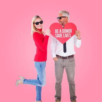 Cool couple holding a red heart together against pink