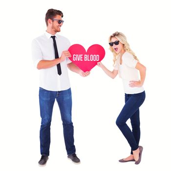 Cool young couple holding red heart against give blood