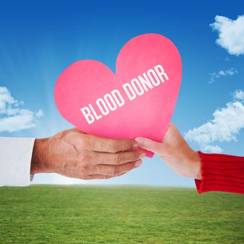 Couple holding heart against sky and field