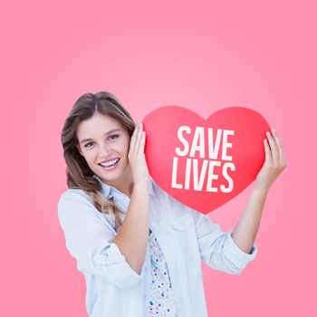 Woman holding heart card  against pink