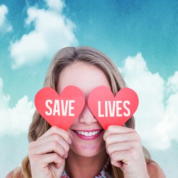 Woman holding heart cards  against blue sky