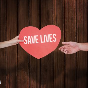 Woman giving heart card to her boyfriend  against wooden planks