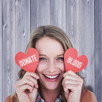 Woman holding heart cards  against wooden planks