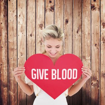 Attractive young blonde showing red heart against wooden planks