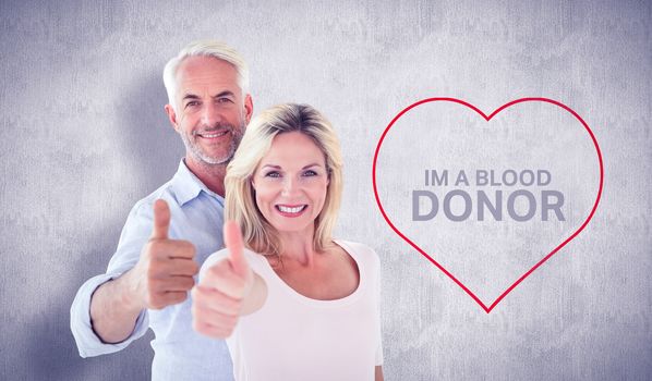 Smiling couple showing thumbs up together against white and grey background