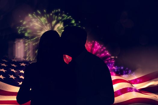 Handsome man giving his wife a kiss on cheek against colourful fireworks exploding on black background