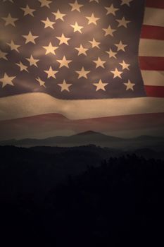 United states of america flag against trees and mountain range against cloudscape