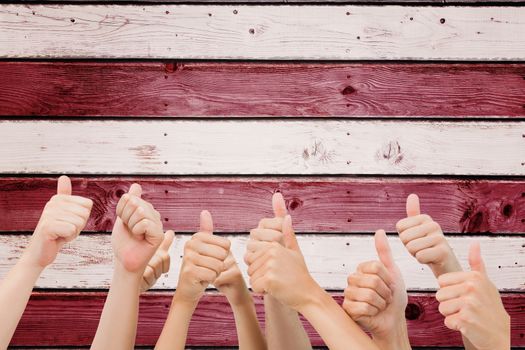 Group of hands giving thumbs up against digitally generated grey wooden planks