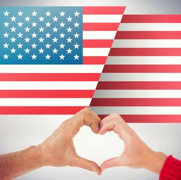 Couple making heart shape with hands against grey background