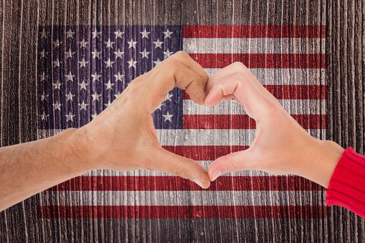 Couple making heart shape with hands against digitally generated grey wooden planks