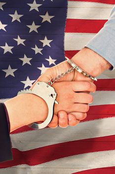 Business people in handcuffs shaking hands against pale grey wooden planks