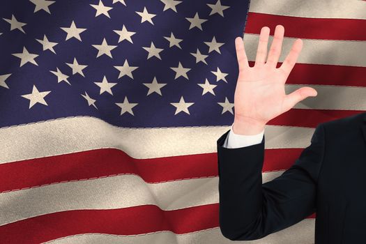 Businessman in suit with hand raised against united states of america flag