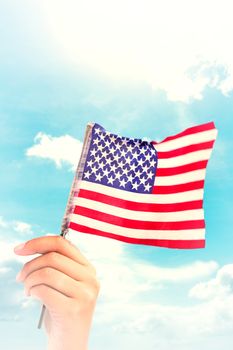 Hand waving american flag against blue sky