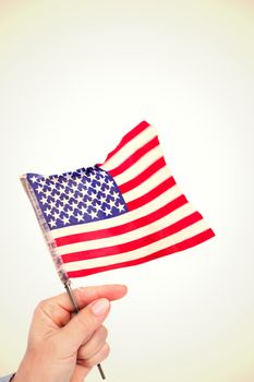 Hand waving american flag against white background with vignette