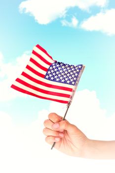 Hand waving american flag against blue sky