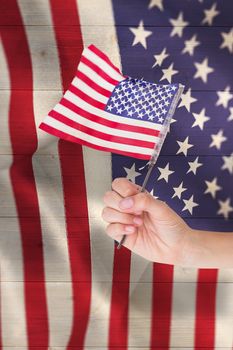 Hand waving american flag against pale grey wooden planks