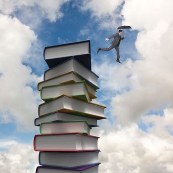 Businessman jumping holding an umbrella against stack of books
