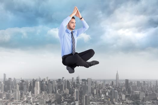 Calm businessman sitting in lotus pose with hands together against cityscape