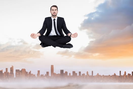 Peaceful businessman sitting in lotus pose relaxing against sandy path leading to large urban city