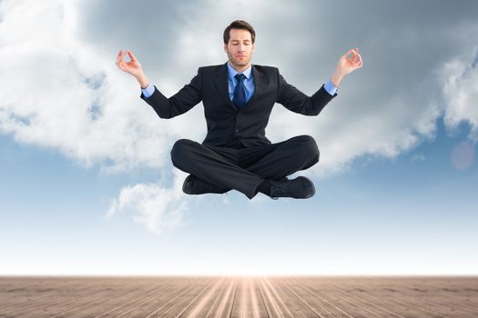 Calm businessman sitting in lotus pose against cloudy sky background