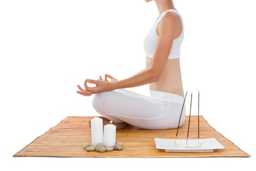 Fit woman meditating on bamboo mat on white background