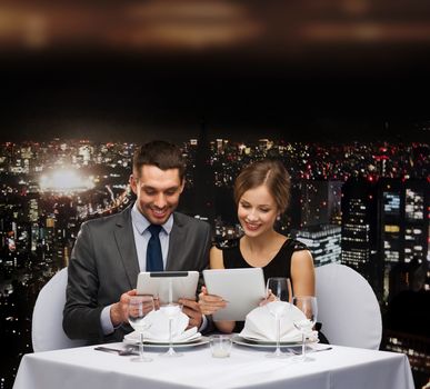 restaurant, couple, technology and holiday concept - smiling couple with menus on tablet pc computers at restaurant