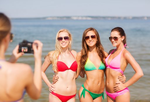 summer vacation, gesture, travel and people concept - group of smiling young women photographing by camera and waving hands on beach