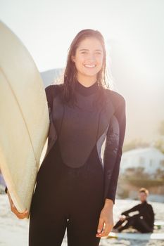 Pretty surfer smiling at camera at the beach
