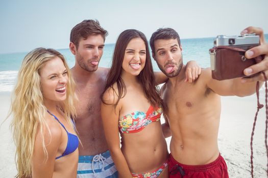 group of friends in swimsuits taking a selfie at the beach