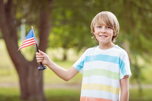 Young boy holding an american flag on a sunny day 