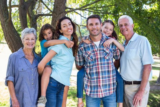 Extended family smiling in the park on a sunny day