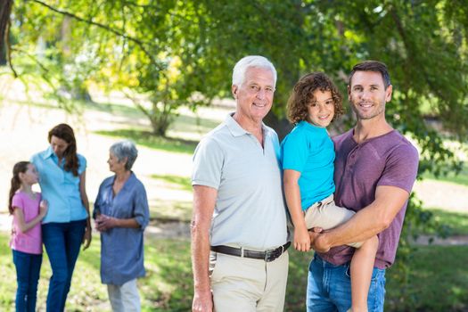 Extended family smiling in the park on a sunny day