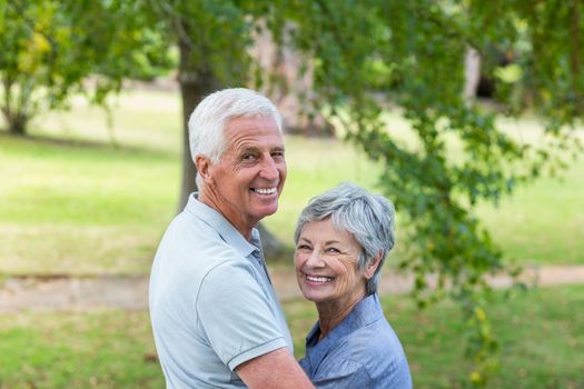 Happy old couple smiling in a park on a sunny day 