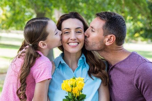 Happy family kissing at camera in the park on a sunny day