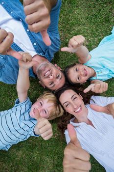 Happy family in the park together thumbs up on a sunny day