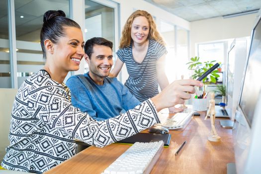 Smiling business team working together with computer in the office