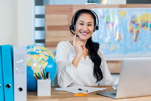 Pretty travel agent smiling at camera in the office