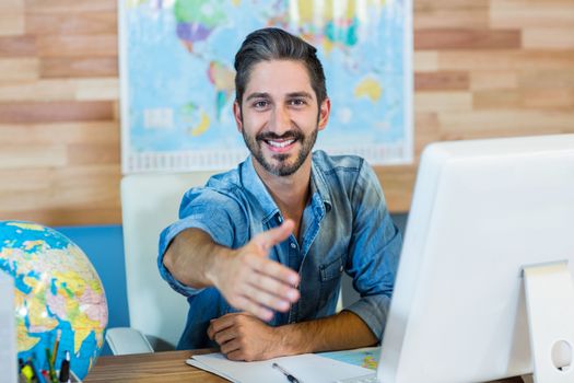 Smiling travel agent presenting his hand in the office