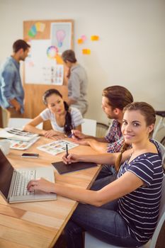 Upward plan of a smiling young businesswoman using laptop at office