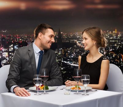 restaurant, couple and holiday concept - smiling couple eating main course with red wine at restaurant