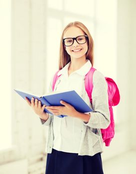 education and school concept - little student girl reading book at school