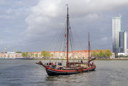 Rotterdam, Netherlands - May 9, 2015: Tourist boat on Nieuwe Maas (New Meuse) river in Rotterdam, Netherlands. The port of Rotterdam is the largest cargo port in Europe and the 10th largest in the world.