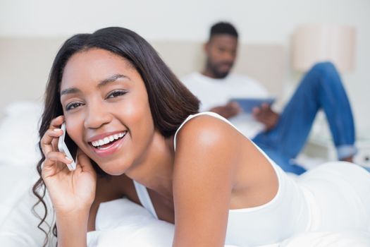 Relaxed couple using technology on bed at home in bedroom